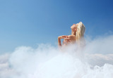 Beautiful blond woman in the clouds throwing back her head