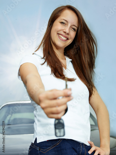 Pretty woman proudly presents the key of her car outdoors photo