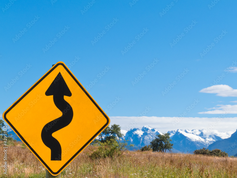 Wavy arrow roadsign and snowy mountain peaks Wavy arrow roadsign and snowy mountain peaks