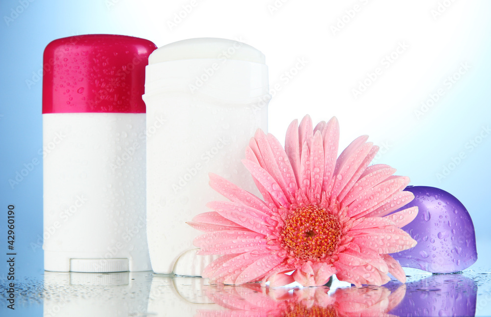 deodorant botttles with flower on blue background deodorant botttles with flower on blue background