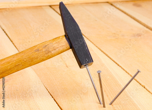Metal nails in wooden plank and hammer