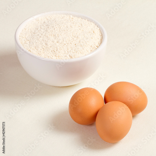 Eggs and wheat flour in a plate on white background