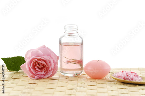 Perfume bottle and Spoon of spa salt with candle on wicker mat