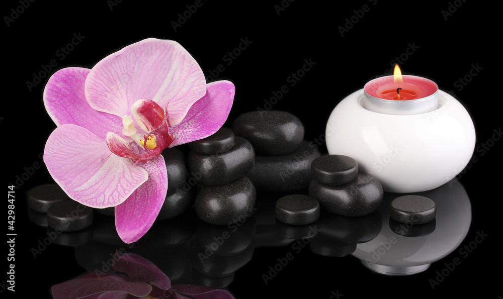 Spa stones with orchid flower and candle isolated on black Spa stones with orchid flower and candle isolated on black