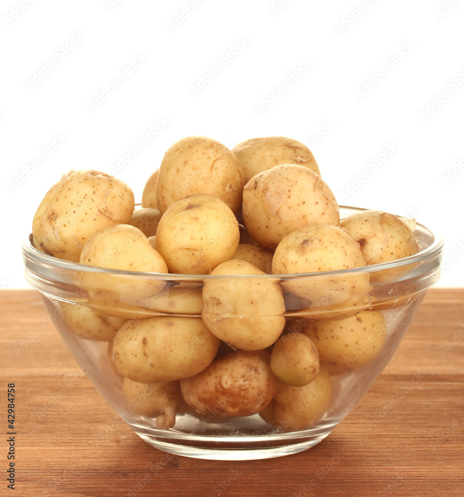 young potatoes in a glass bowl on a table on white background young potatoes in a glass bowl on a table on white background