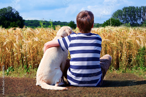 Junge mit Labrador Retriever vor Getreidefeld photo