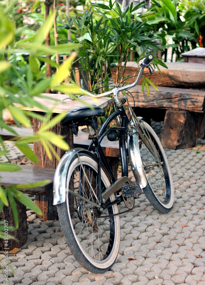 a black bicycle leaning against wooden table
