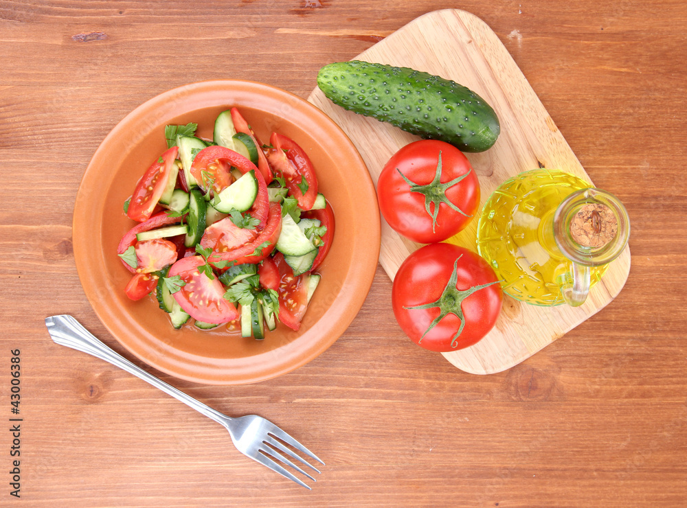 Fresh salad with tomatoes and cucumbers on wooden background Fresh salad with tomatoes and cucumbers on wooden background