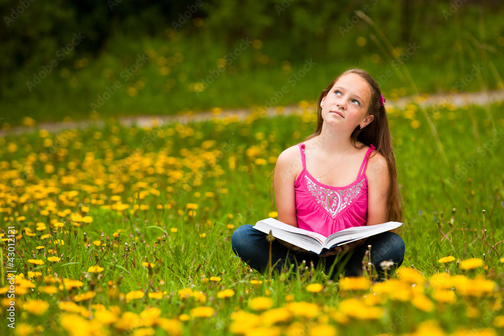 Little girl sits on a grass and dreams while reading a book Little girl sits on a grass and dreams while reading a book
