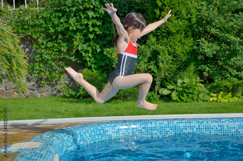 Happy active child jumps to swimming pool, girl having fun