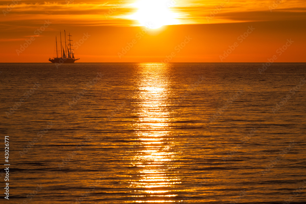 Sail ship silhouette at sea and sun