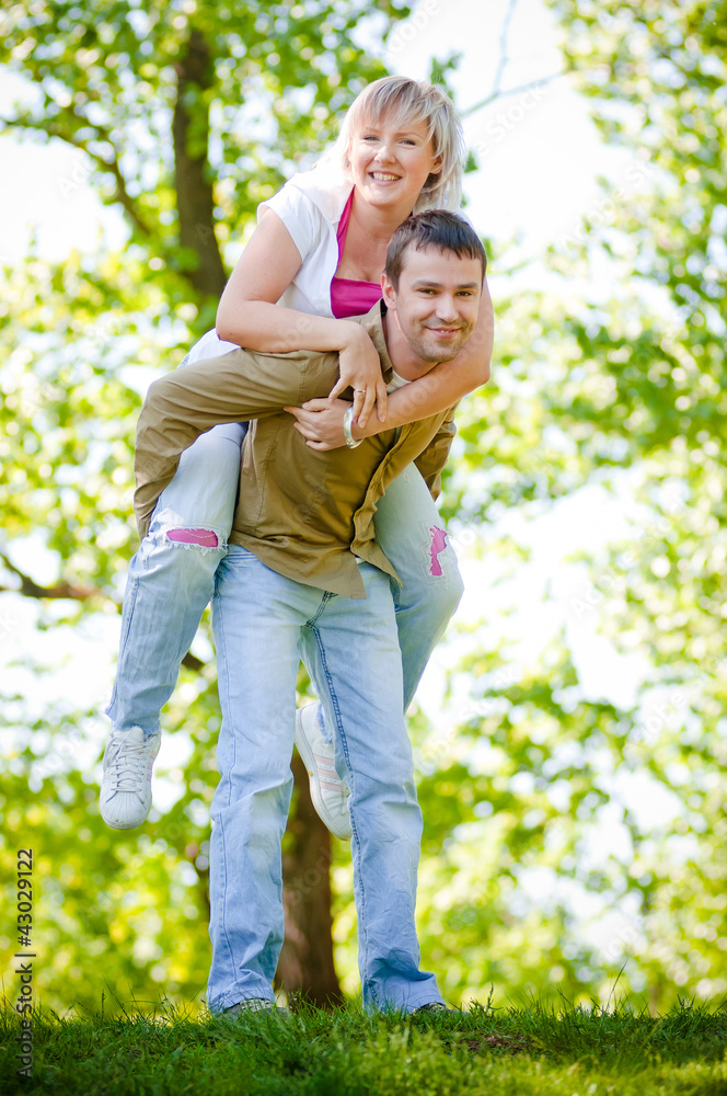 young couple man holds woman on his back