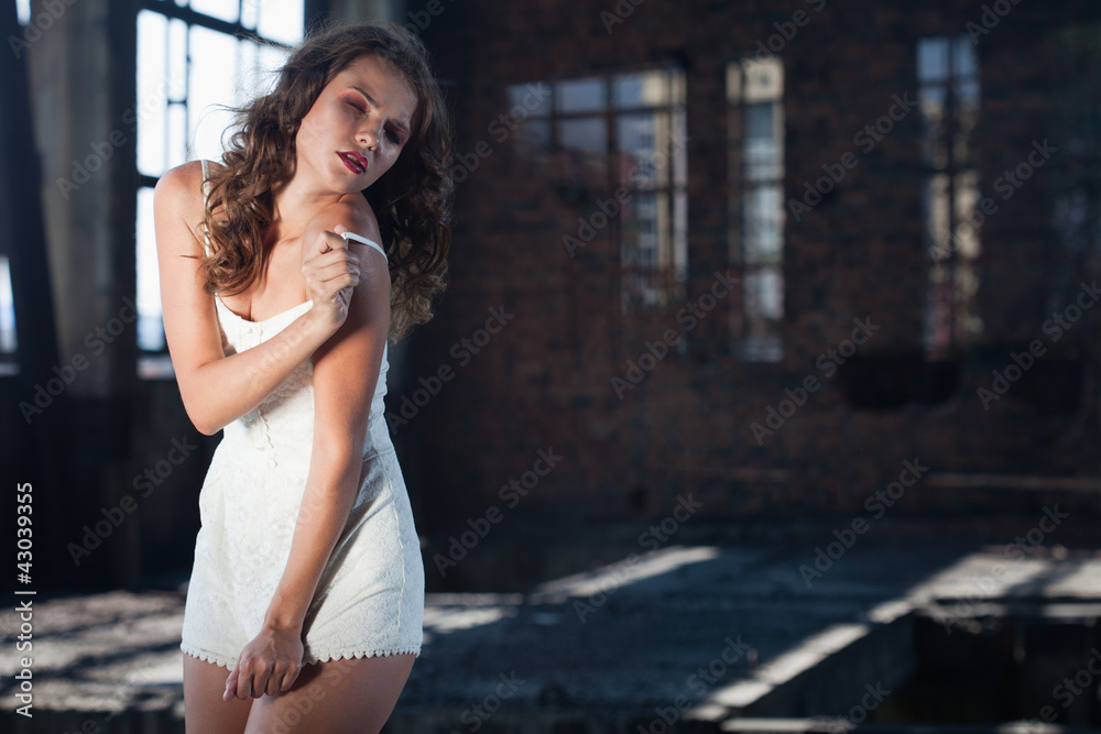 Fototapeta premium Young brunette posing against the backdrop of a building with l