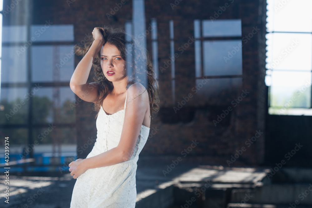 Young  brunette posing against the backdrop of a building with l