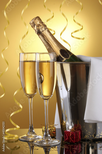 Champagne bottle in bucket with ice and glasses of champagne,