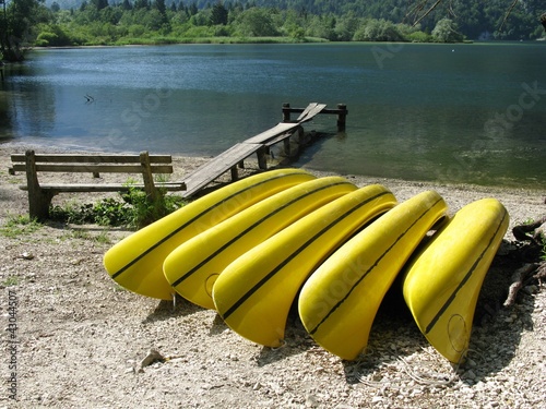 Fotografia Yellow canoes in a row on the beach of a lake