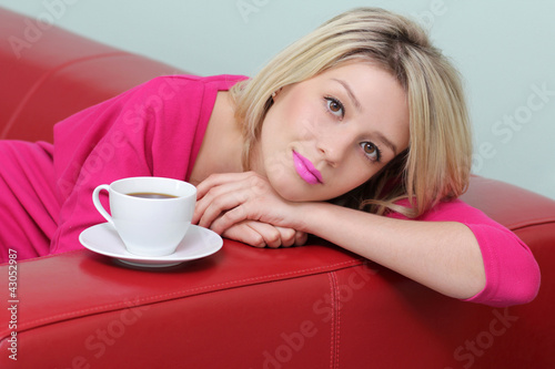 Blonde sits on the couch with a cup of coffee