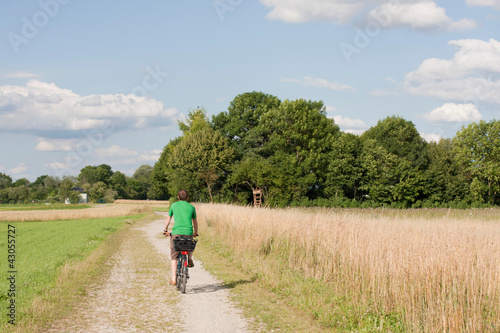 Junger Mann fährt Fahrrad auf Feldweg