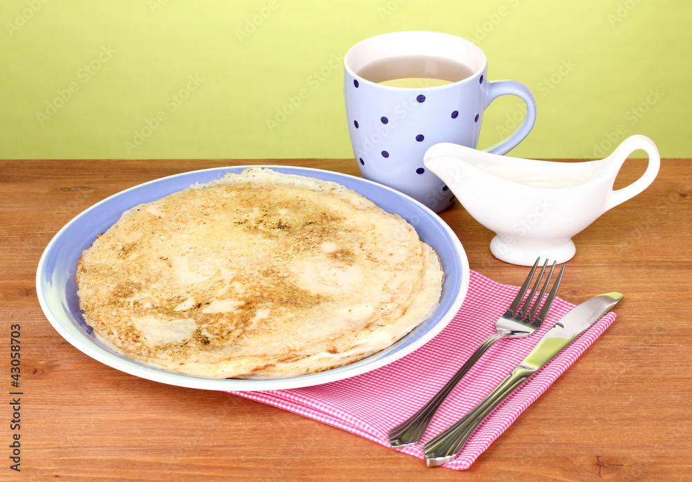 Stack of tasty pancakes on wooden table on green background Stack of tasty pancakes on wooden table on green background