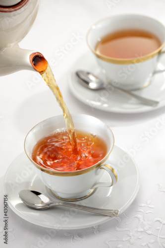 Pouring tea from the tea pot to the cups