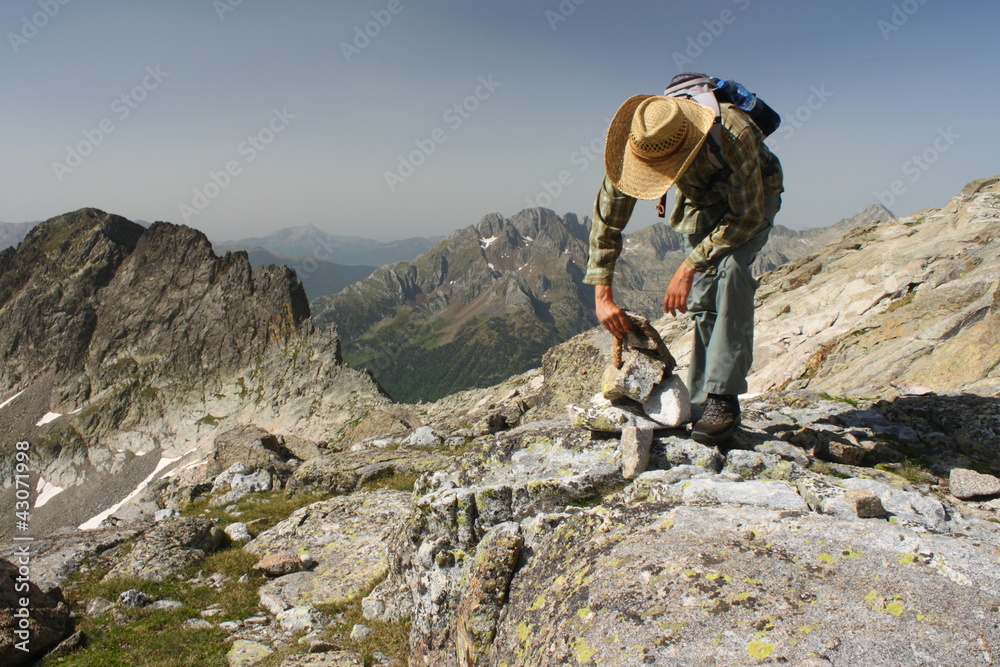 walker making a cairn in Pyrenees