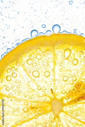 close-up of lemon slice in clear water with bubbles
