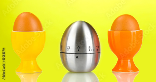 egg timer and egg in color stand on green background