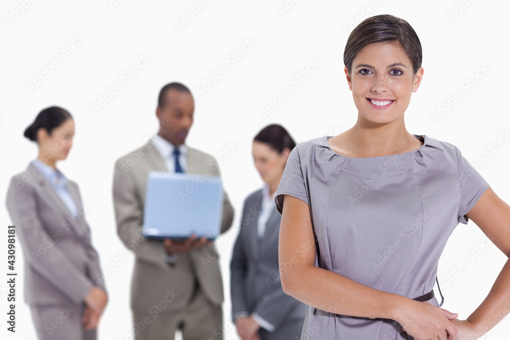 Woman with hands on her hips with business team in the backgroun Woman with hands on her hips with business team in the backgroun