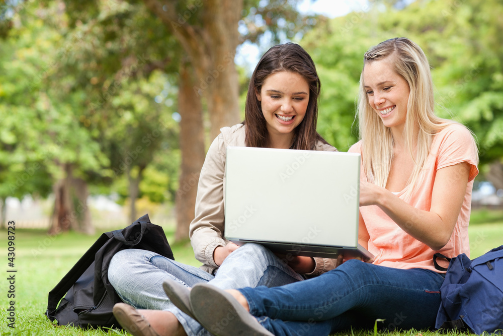 Laughing teenagers sitting while using a laptop Laughing teenagers sitting while using a laptop