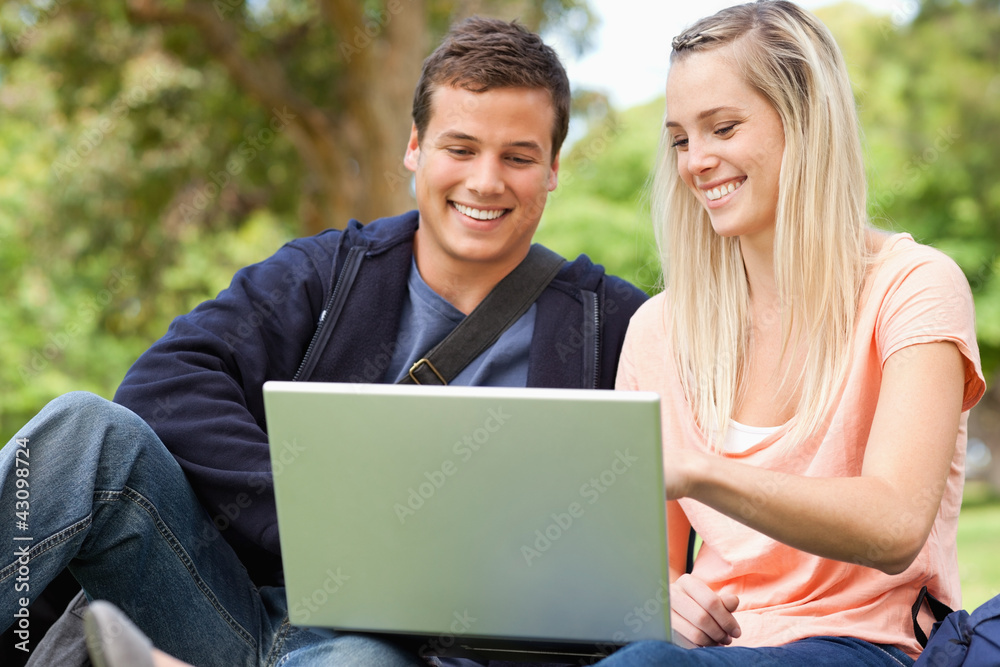 Young people sitting while using a laptop Young people sitting while using a laptop