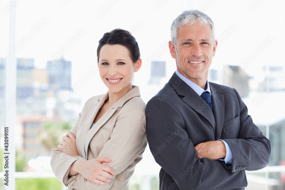 Mature businessman and his secretary standing upright side by si Mature businessman and his secretary standing upright side by si