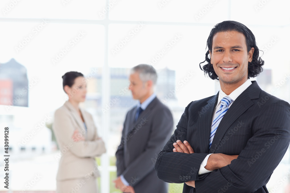 Executive crossing his arms in front of two business people Executive crossing his arms in front of two business people