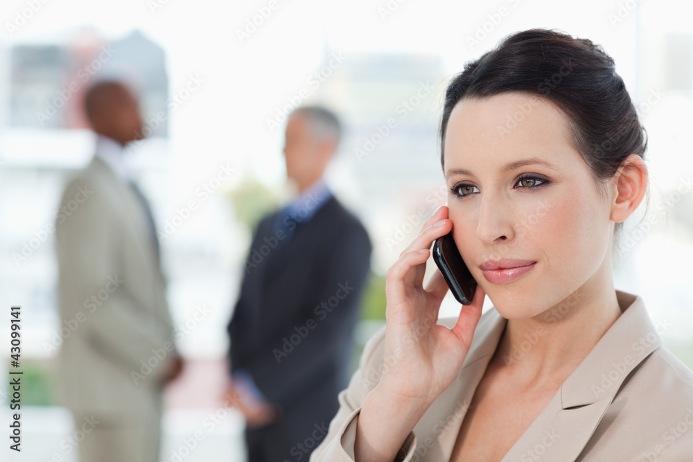 Young secretary using mobile phone in front of two businessmen Young secretary using mobile phone in front of two businessmen