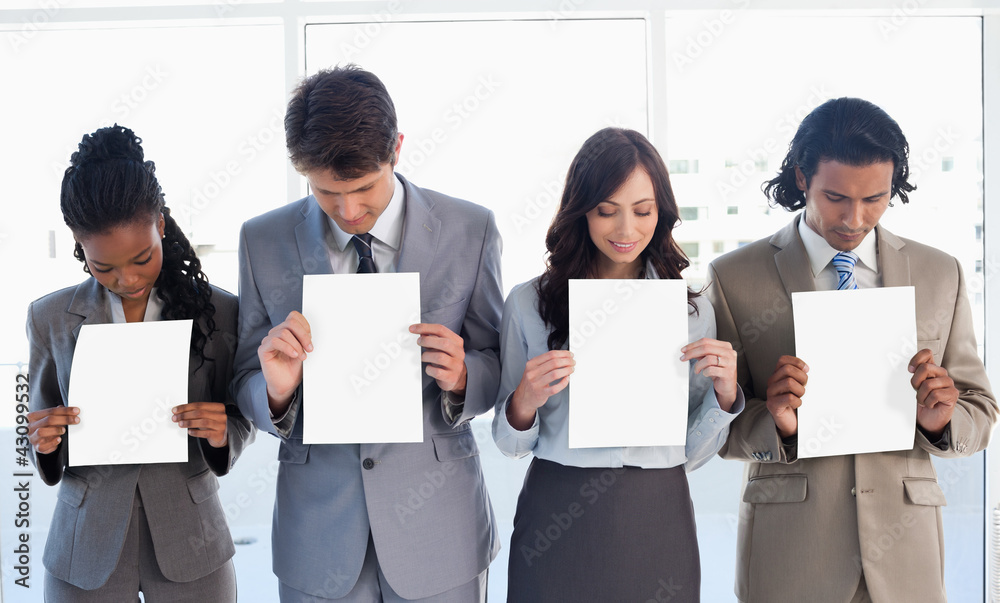 Young business team showing blank sheets while bowing their head Young business team showing blank sheets while bowing their head