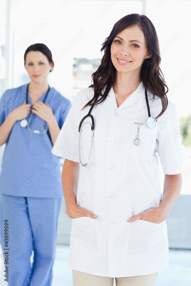A nurse standing upright while her colleague is standing behind A nurse standing upright while her colleague is standing behind