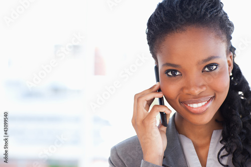 Young smiling businesswoman looking ahead while talking on a pho