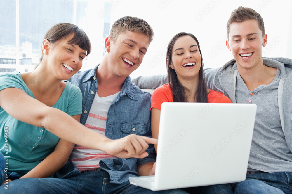A group of smiling friends gathered around a laptop A group of smiling friends gathered around a laptop