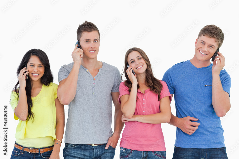 A smiling group of friends make calls while looking into the cam A smiling group of friends make calls while looking into the cam