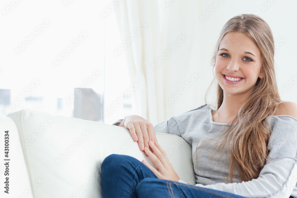 A smiling girl looking into the camera as she sits on the couch A smiling girl looking into the camera as she sits on the couch
