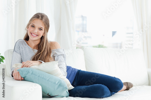 A smiling girl lying on the couch facing the camera