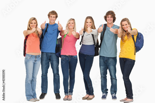 Smiling group giving a thumbs up as they wear backpacks