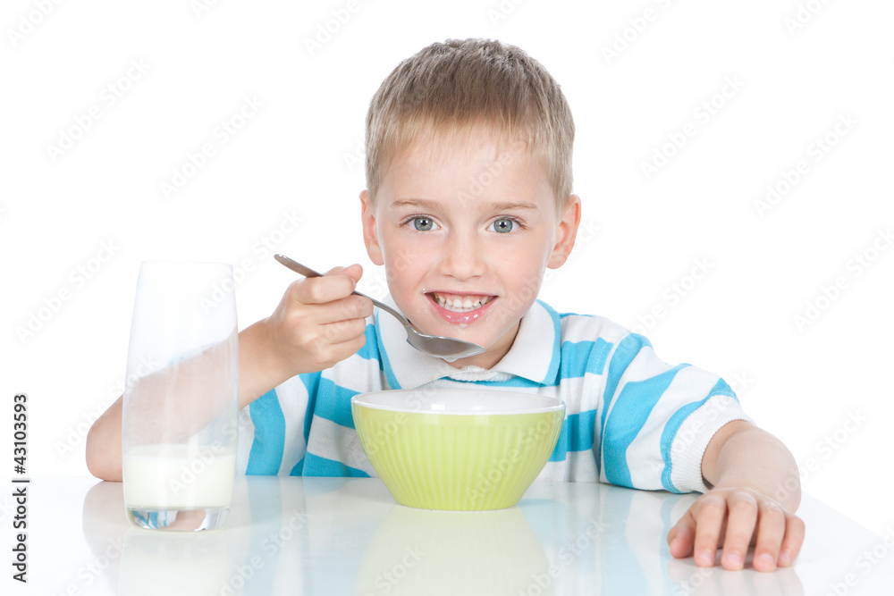 Little smiling boy eating breakfast on white
