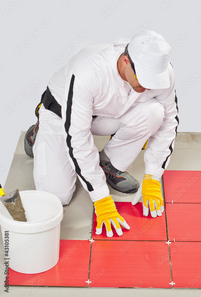 worker with bucket adhesive apply red tiles