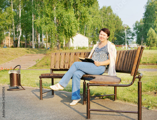 Woman reads a book on a bench in the park