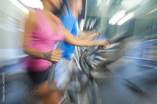 Motion Blur Zoom Man & Woman Using Gym Equipment