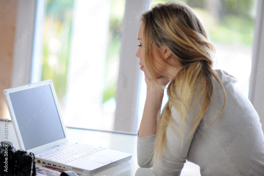 Woman sitting in front of laptop with thoughtful look Woman sitting in front of laptop with thoughtful look