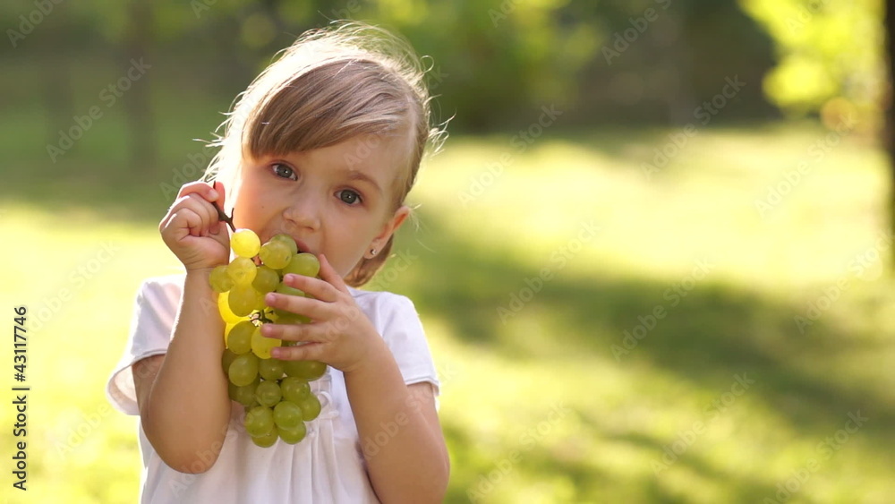 Girl eagerly eating grapes outdoors