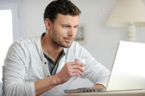 Man drinking coffee in front of laptop computer