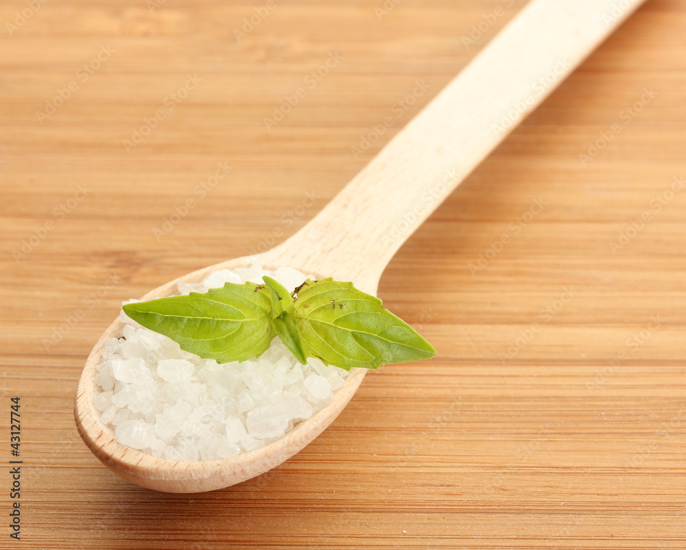 salt in spoon with fresh basil on wooden background salt in spoon with fresh basil on wooden background