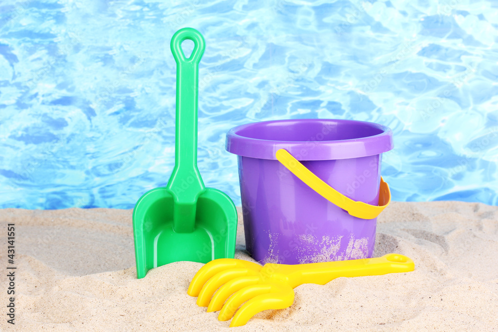 Children's beach toys on sand on water background Children's beach toys on sand on water background